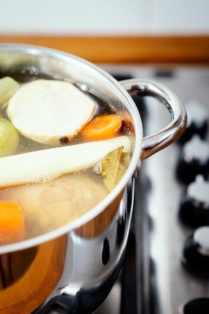pot with boiling delicious and fragrant broth on the gas stove in the kitchenの写真素材