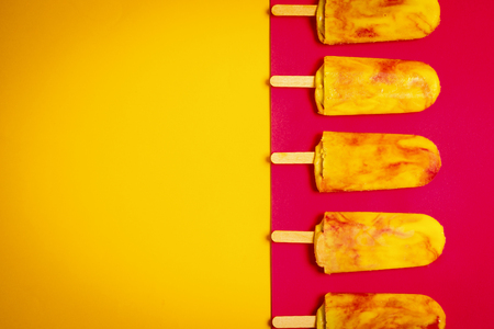 isolated delicious yellow-red ice cream on a colorful summer backgroundの写真素材