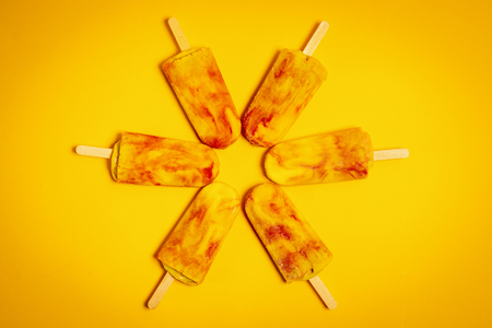 isolated delicious yellow-red ice cream on a colorful summer backgroundの写真素材