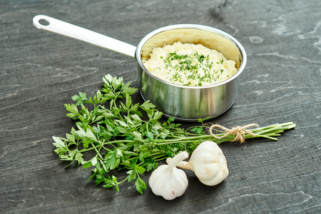 delicious and creamy puree of fresh potatoes sprinkled with parsley in a silver pot on a black tableの写真素材