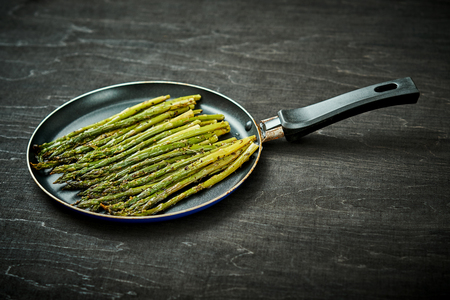 delicious and juicy green asparagus in a pan on an old wooden black tableの写真素材