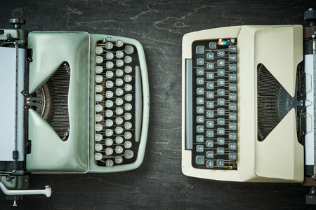 two old typewriters on a black wooden tableの写真素材