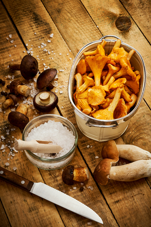 delicious yellow and fresh chanterelle mushrooms in a bowl on an old wooden tableの写真素材