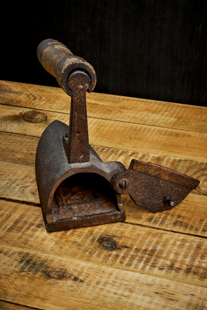 vintage old rusty iron on a bright wooden table next to a black wallの写真素材