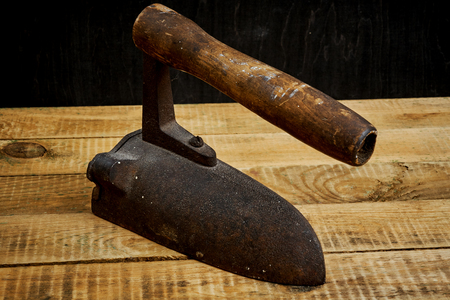 vintage old rusty iron on a bright wooden table next to a black wallの写真素材