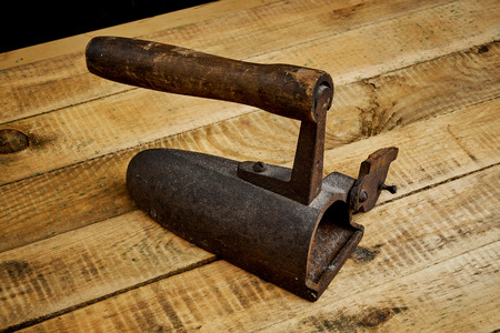 vintage old rusty iron on a bright wooden table next to a black wallの写真素材