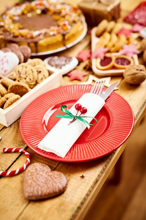 old wooden table with a red plate with knife and fork and various decorationsの写真素材