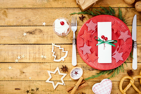 beautiful Christmas Eve background on an old wooden table with a red plate with a knife and forkの写真素材