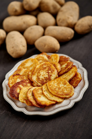 delicious golden potato pancakes on an old wooden black table in the kitchenの写真素材