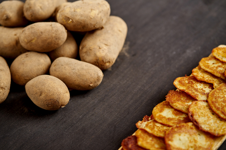 delicious golden potato pancakes on an old wooden black table in the kitchenの写真素材