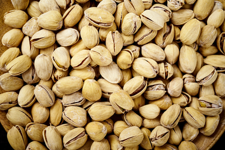 background full of delicious pistachios on an old wooden black table in a pub