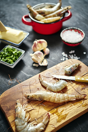 fresh delicious raw tiger prawns in a red pot with parsley, lemon, butter and garlicの写真素材