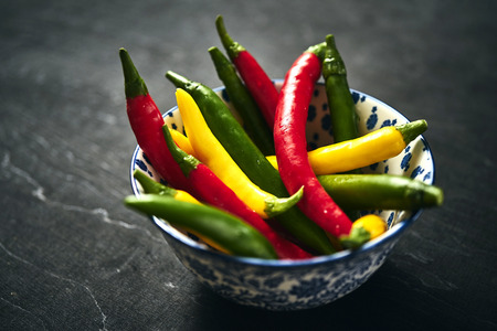 several fresh and colorful chili peppers in a bowlの写真素材