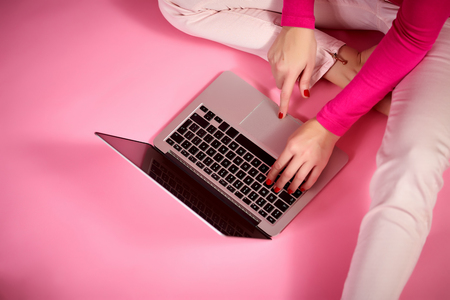female hands on a laptop keyboard, businesswoman, on a light pink backgroundの写真素材