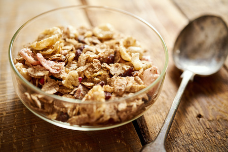 Healthy morning breakfast bowl full of organic granola with a rustic spoon on an wooden tableの写真素材