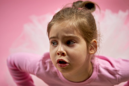portrait of a cute little girl in tulle skirt on a pink backgroundの写真素材