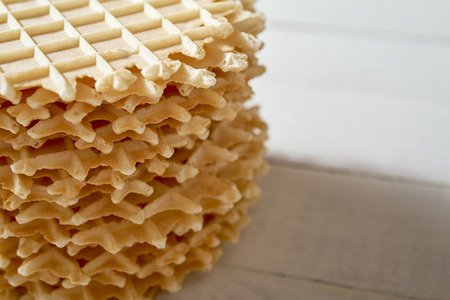 Crisp golden waffles wafer biscuits used for garnishing desserts on bright wooden table.の写真素材