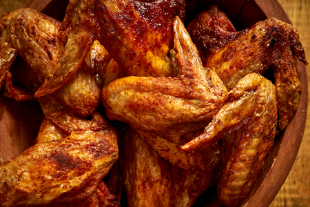 Close up of delicious grilled chicken wings in wooden bowl on wooden table.の写真素材