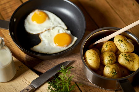 Fried egg with young potatoes with dill and milk on  wooden tableの写真素材