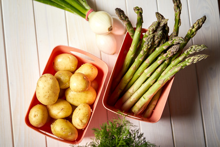 Fresh asparagus potatoes and chives on white  kitchen tableの写真素材