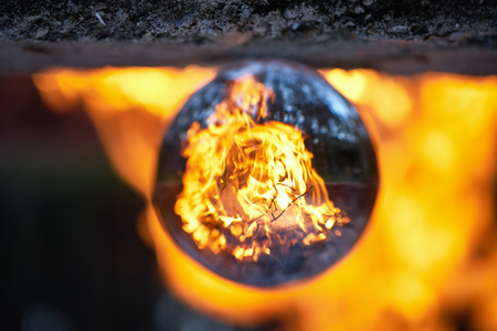 Upside down view through the lensball on blurred campfire in the evening forestの写真素材