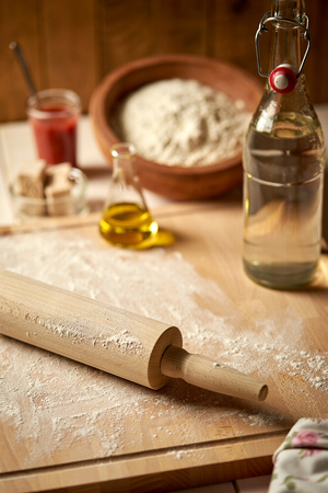 Ingredients for pizza dough flour with olive oil and yeast on wooden kitchen tableの写真素材
