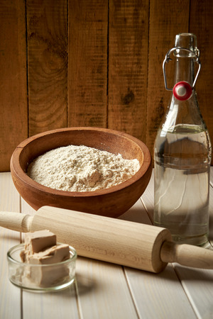 Ingredients for pizza dough flour with olive oil and yeast on wooden kitchen tableの写真素材