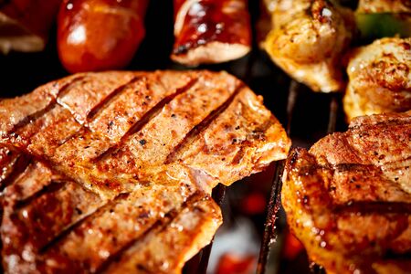 Juicy beef steaks on hot grill with flame on barbecue in the garden