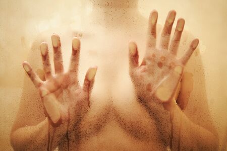 Blurred view on sexy girl in shower behind wet glass .の写真素材