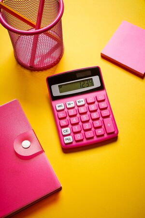 Closeup of calculator and notebook with pencil on yellow deskの写真素材