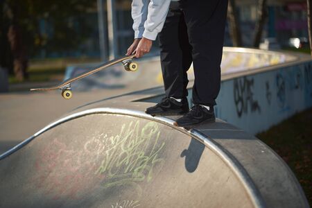 Man with beard in skatepark rides skateboard on warm autumn day