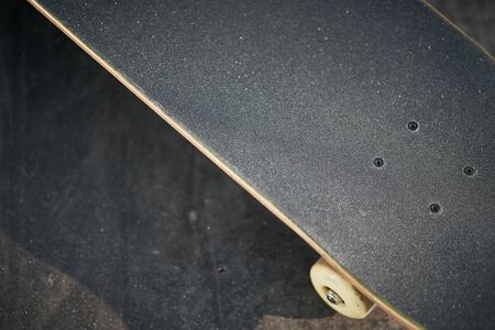 Top view of black skateboard in concrete skatepark on warm summer day