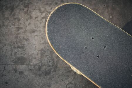 Top view of black skateboard in concrete skatepark on warm summer day