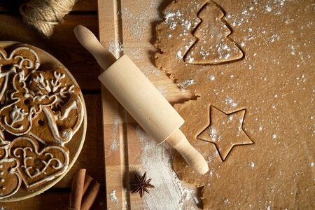 Dough for Christmas gingerbread and cookie cutters on wooden table