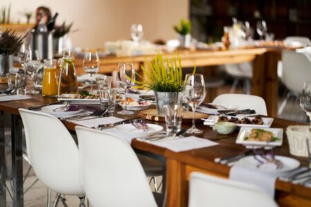 Elegant tables with setting for party or wedding with dishes and glasses and on sunny summer dayの写真素材