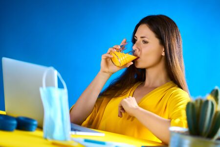 woman drinks juice and works during quarantine