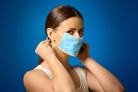 woman in white shirt shows how to wear a mask during a pandemicの写真素材