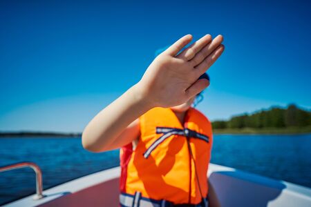 blurry little girl hides her face behind her hand on a motorboatの写真素材