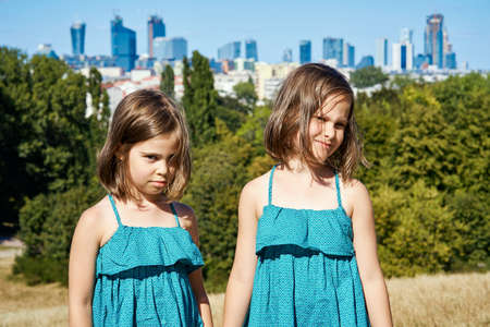 two cute girls in dresses are posing on the city skyline in summerの写真素材