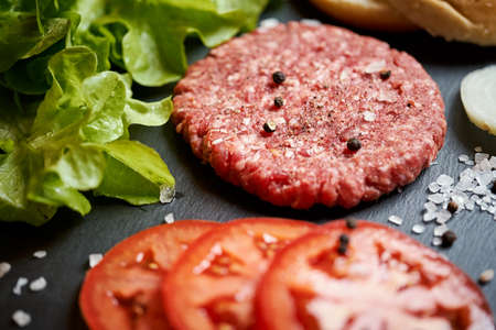 fresh beef for burger on the table with lettuce onion and breadの写真素材