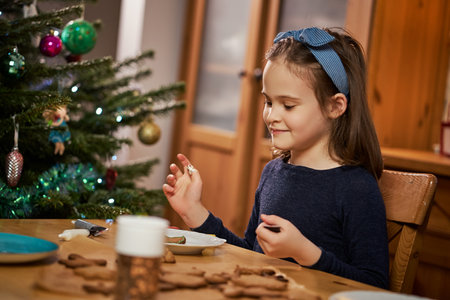 cute girl makes and decorates christmas gingerbreadsの写真素材