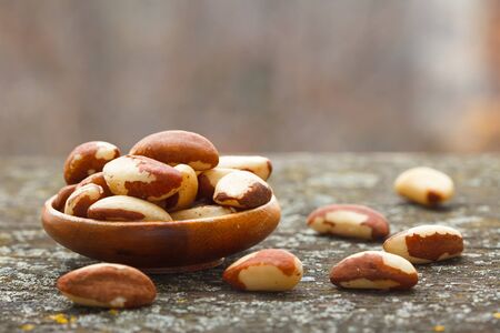 Healthy Brazil nuts in wooden bowl on rustic table.