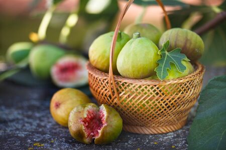 Fresh figs in wicker basket. Cracked ripe fig on rustic table.