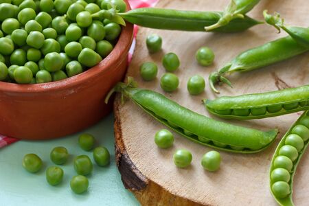 Healthy fresh green peas in clay bowl and podsの写真素材