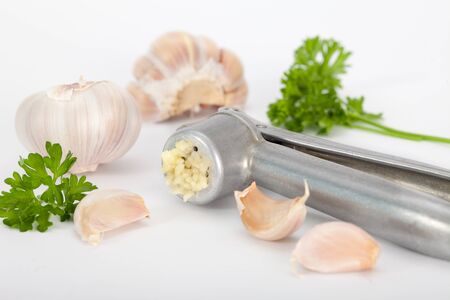 Garlic bulb and garlic cloves with garlic press on white backgroundの写真素材