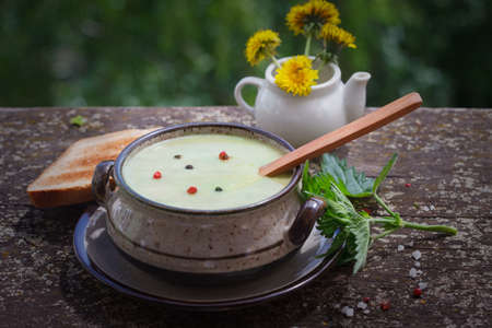 Nettle soup with toast bread on wooden background.