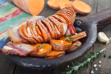 Homemade Cooked Sweet Potato with fried bacon and herbs. Hasselback baked potato.の写真素材