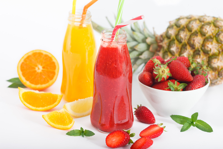 Summer Fruit cocktail smoothie with strawberries, pineapple and orange in bottles. White background.の写真素材