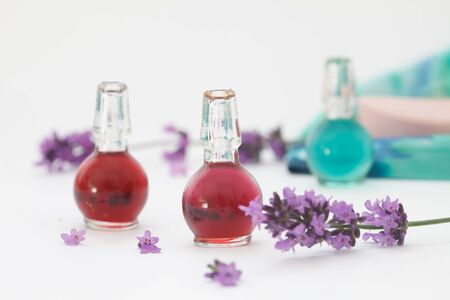 Lavender essential oil in small bottles with fresh lavender petals and flowers. Lavender aromatherapy, spa concept. Natural herb cosmetic with lavender flowers on white backgroundの写真素材