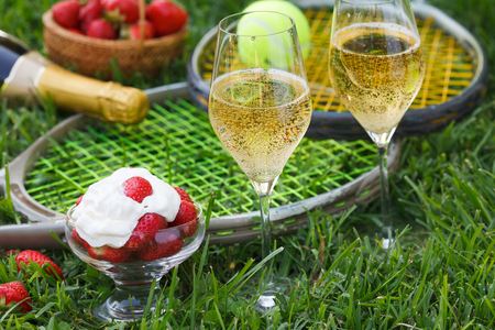 Enjoing in Wimbledon tennis championship with champagne and strawberries with cream. Wimbledon symbols on green grass.の写真素材